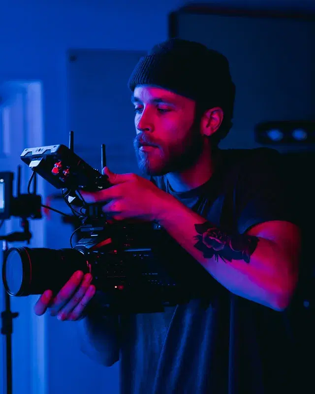 A filmmaker operating a cinema camera under neon light